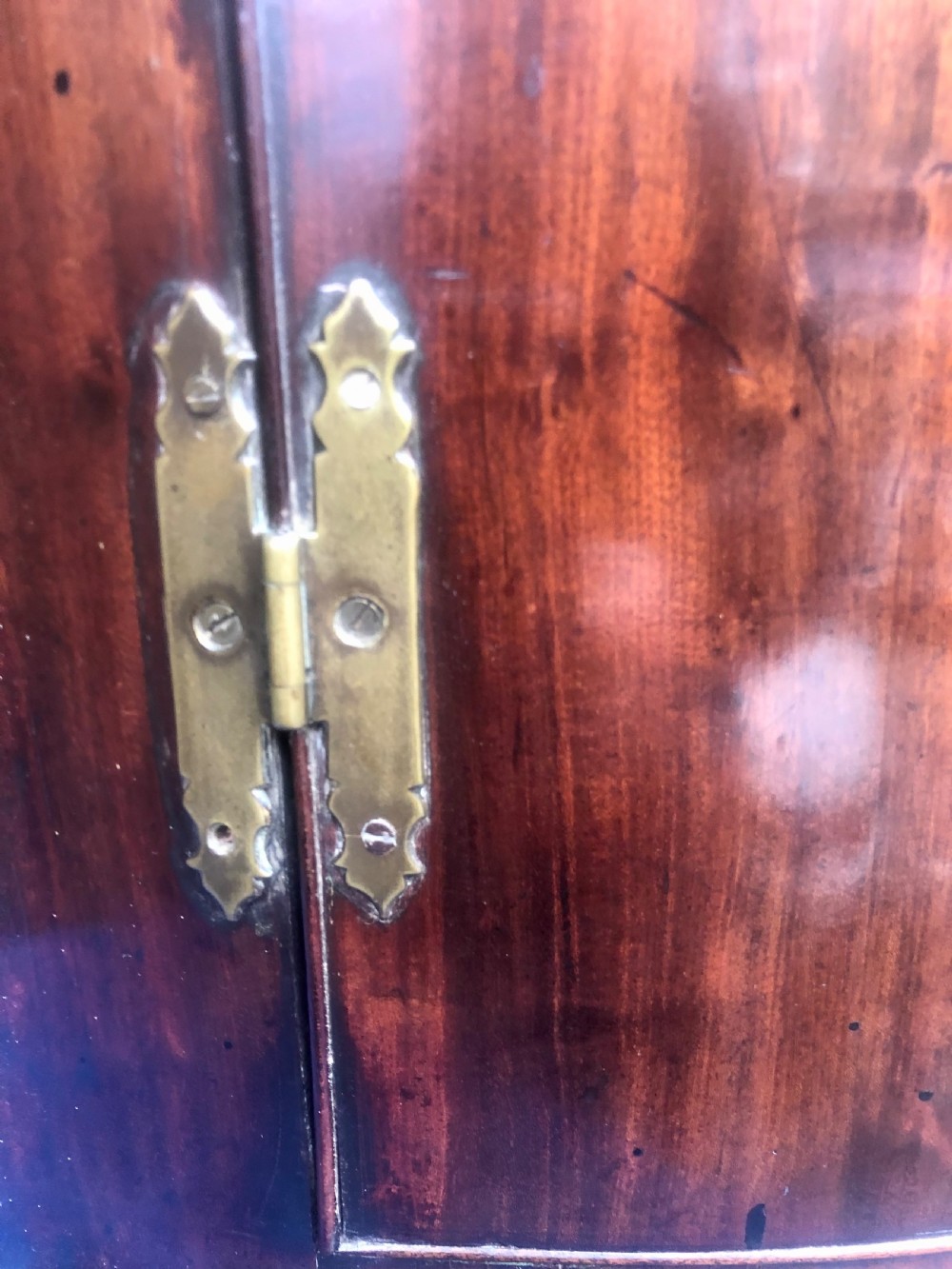 A Georgian bow-fronted mahogany corner cupboard with double doors, brass keyhole escutcheons, and visible brass hinges. View IX
