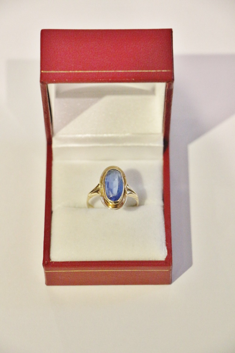 A 14ct yellow gold ring featuring an oval bezel-set blue gemstone on a plain gold band.