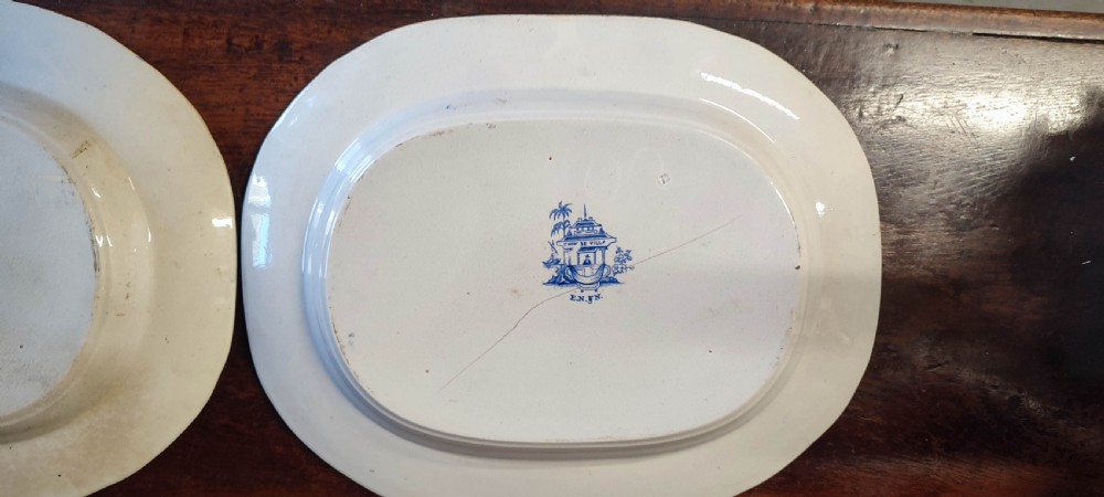A pair of 19th-century oval earthenware meat dishes featuring blue transfer-printed chinoiserie landscape scenes with pagodas, boats, and detailed geometric borders. View X