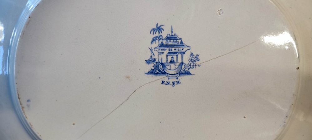 A pair of 19th-century oval earthenware meat dishes featuring blue transfer-printed chinoiserie landscape scenes with pagodas, boats, and detailed geometric borders. View XI