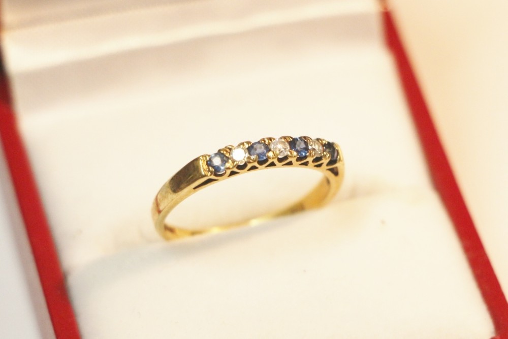 A 9ct yellow gold band set with an alternating row of round-cut blue sapphires and small diamonds.