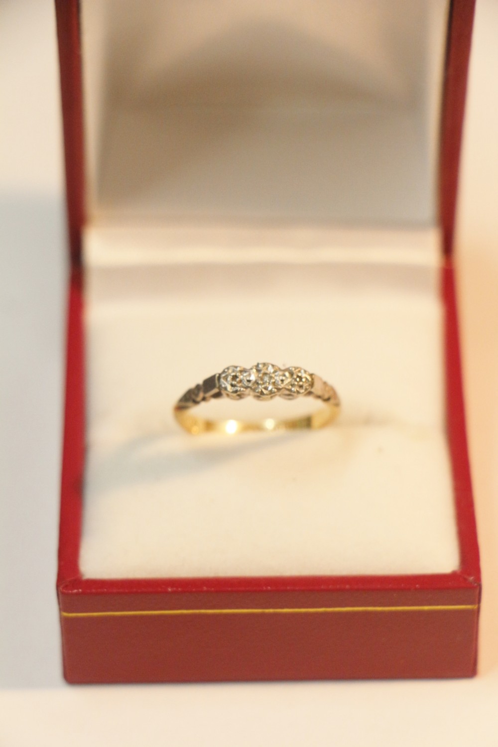 An antique three-stone diamond ring featuring a yellow gold band and a platinum setting with three round diamonds.