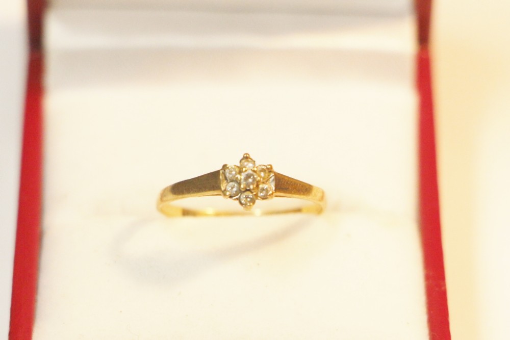 A yellow gold ring featuring a central floral cluster of round diamonds set on a smooth tapered band.
