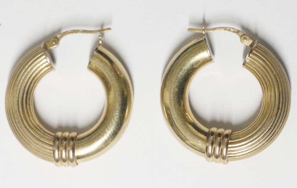 A pair of 9ct yellow gold Grecian style hoop earrings featuring fluted ribbed detailing, central triple-band collars, and hinged wire closures.