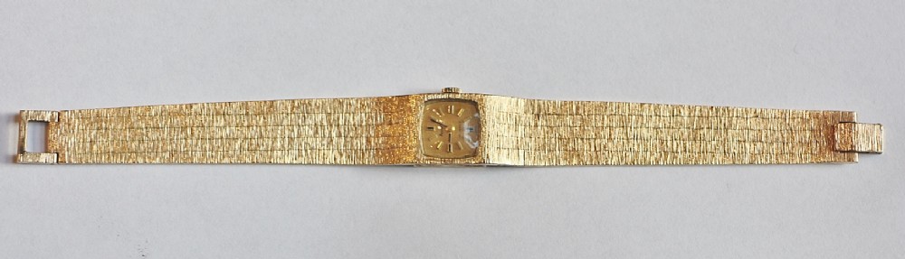 A vintage 9ct solid gold ladies Accurist wristwatch featuring a square dial and a textured bark-effect integrated bracelet.