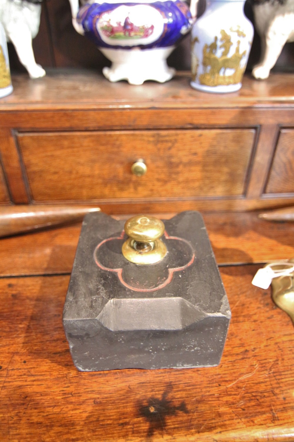 A rectangular block of dark grey Welsh slate featuring carved bevelled edges, a central brass knob, and incised red decorative lines.
