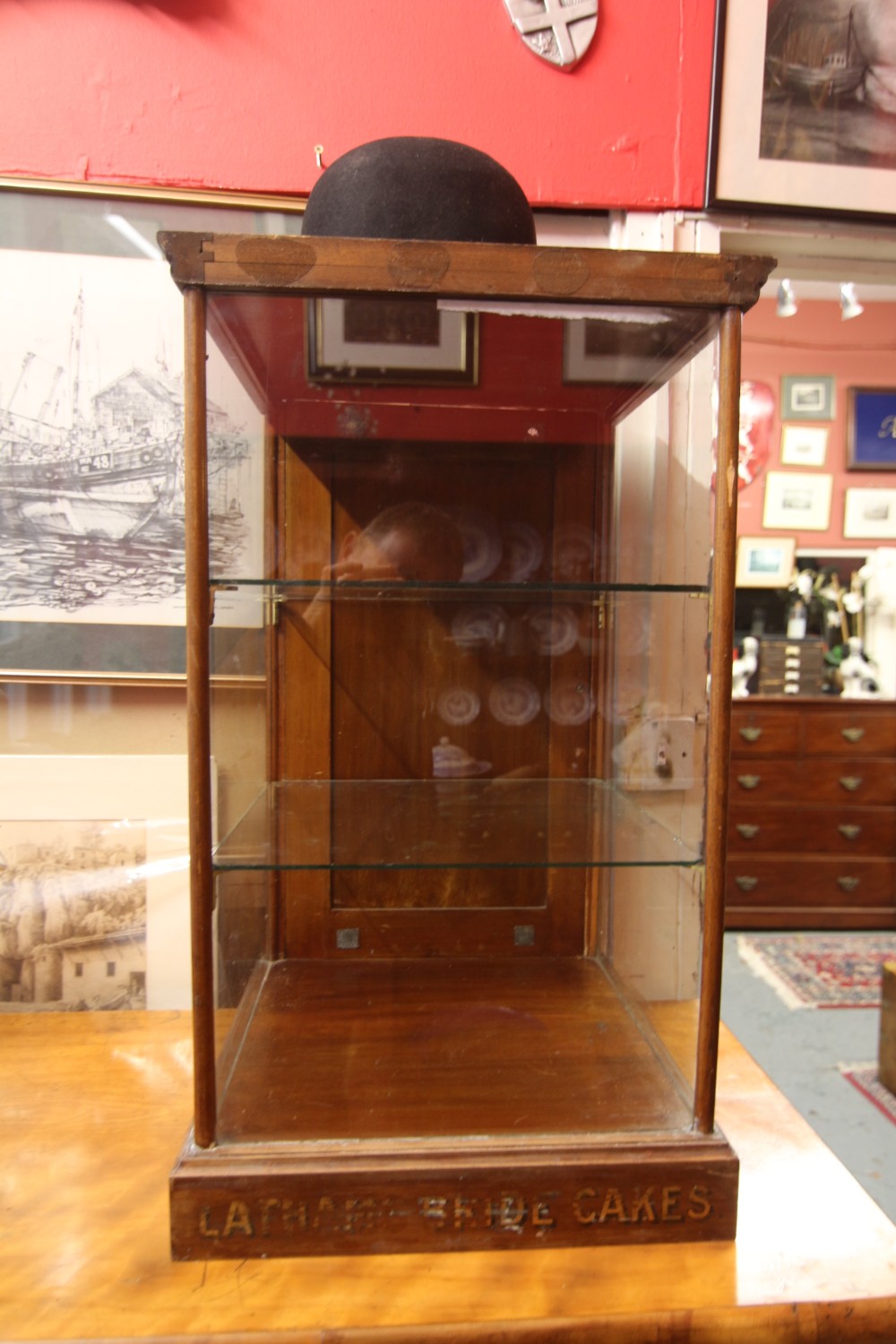 An Edwardian glazed wooden countertop display cabinet featuring gilt lettering on the base reading Lathams Bride Cakes and two internal glass shelves.