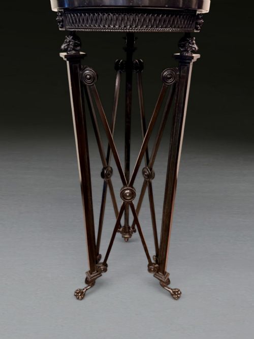 fig 1. A tall Regency dark patinated bronze tripod stand featuring a circular marble top, classical roundels, crossed leg supports, and lion paw feet.