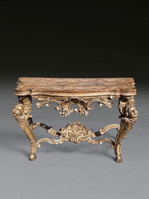 fig 1. An 18th-century Italian giltwood console table featuring carved masks, scrolling stretchers, and a shaped marble top.