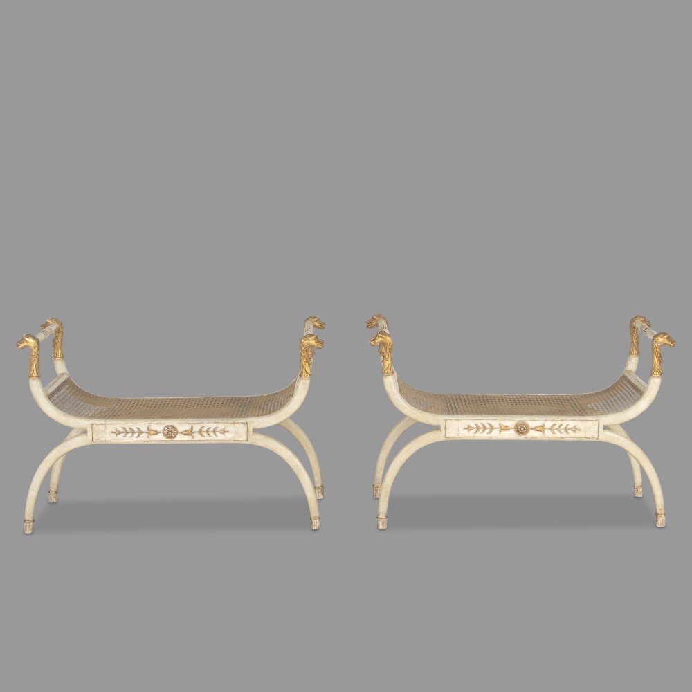 A pair of 19th-century Italian Empire window seats painted cream with gold carved animal head terminals and woven cane seats.