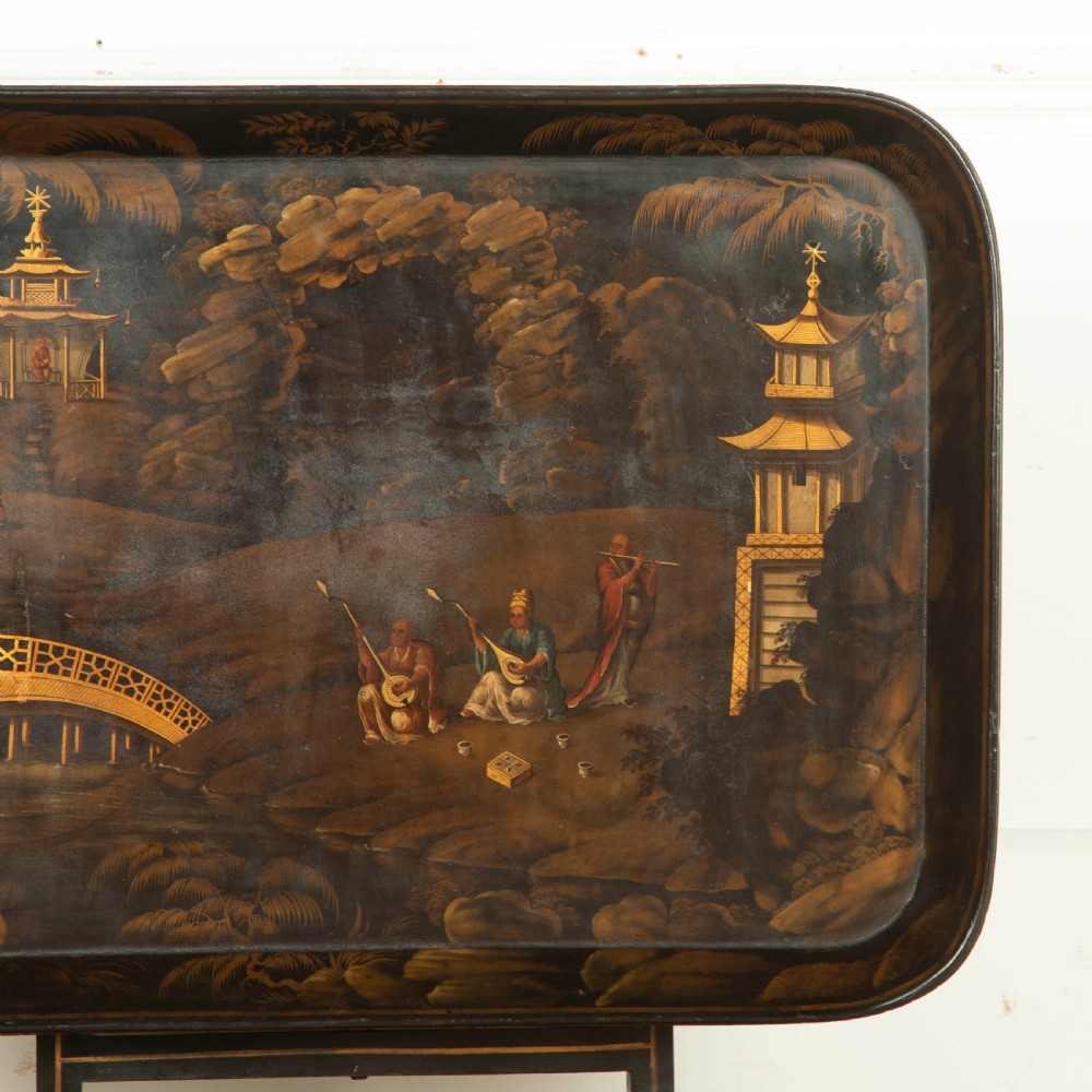 A Regency black lacquered and gilded papier-mache Chinoiserie tray featuring hand-painted pagodas and figures mounted on a dark wooden stand. View IV