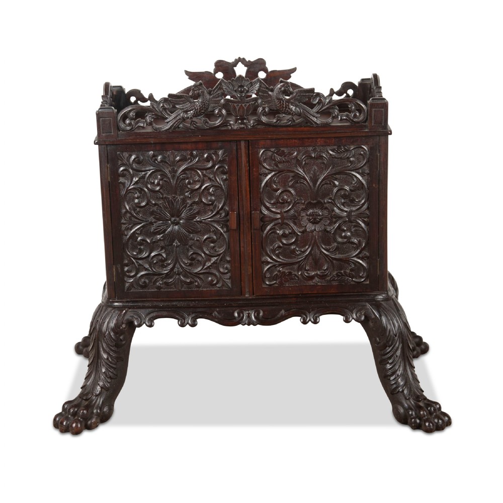 A small 19th-century dark hardwood Chinese cabinet featuring floral relief carving on double doors, an ornate carved cresting gallery, and heavy carved cabriole legs.