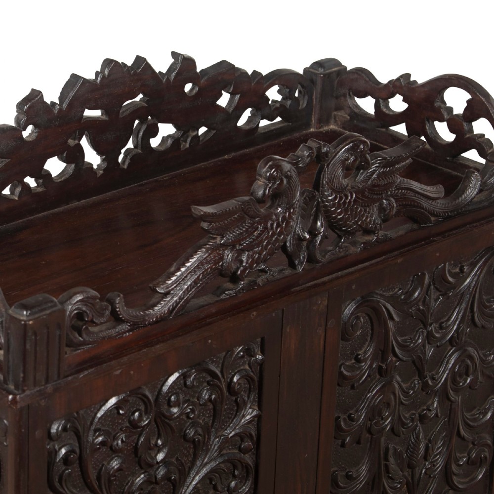 A small 19th-century dark hardwood Chinese cabinet featuring floral relief carving on double doors, an ornate carved cresting gallery, and heavy carved cabriole legs. View IV