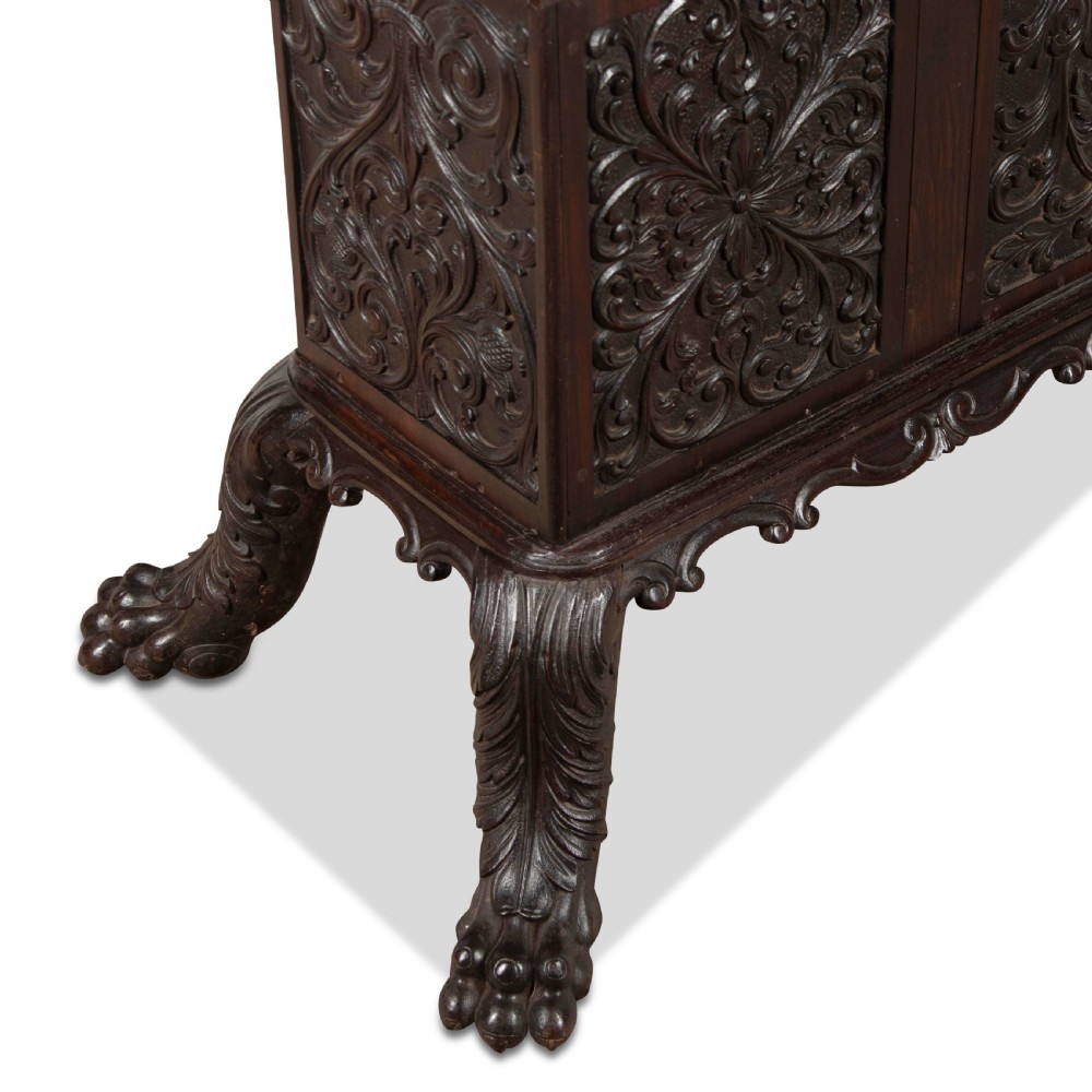A small 19th-century dark hardwood Chinese cabinet featuring floral relief carving on double doors, an ornate carved cresting gallery, and heavy carved cabriole legs. View V