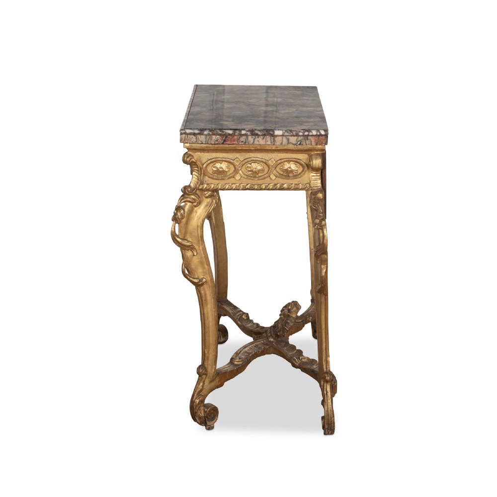 An 18th-century giltwood console table featuring a dark mottled marble top, carved apron with rosette motifs, and cabriole legs linked by an X-shaped stretcher. View V