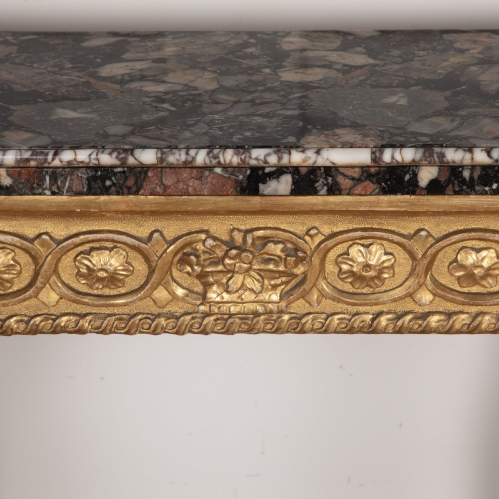 An 18th-century giltwood console table featuring a dark mottled marble top, carved apron with rosette motifs, and cabriole legs linked by an X-shaped stretcher. View VII
