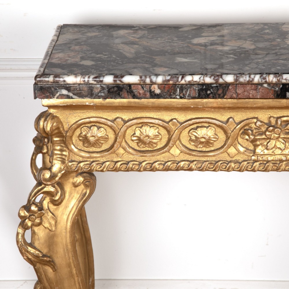 An 18th-century giltwood console table featuring a dark mottled marble top, carved apron with rosette motifs, and cabriole legs linked by an X-shaped stretcher. View VIII