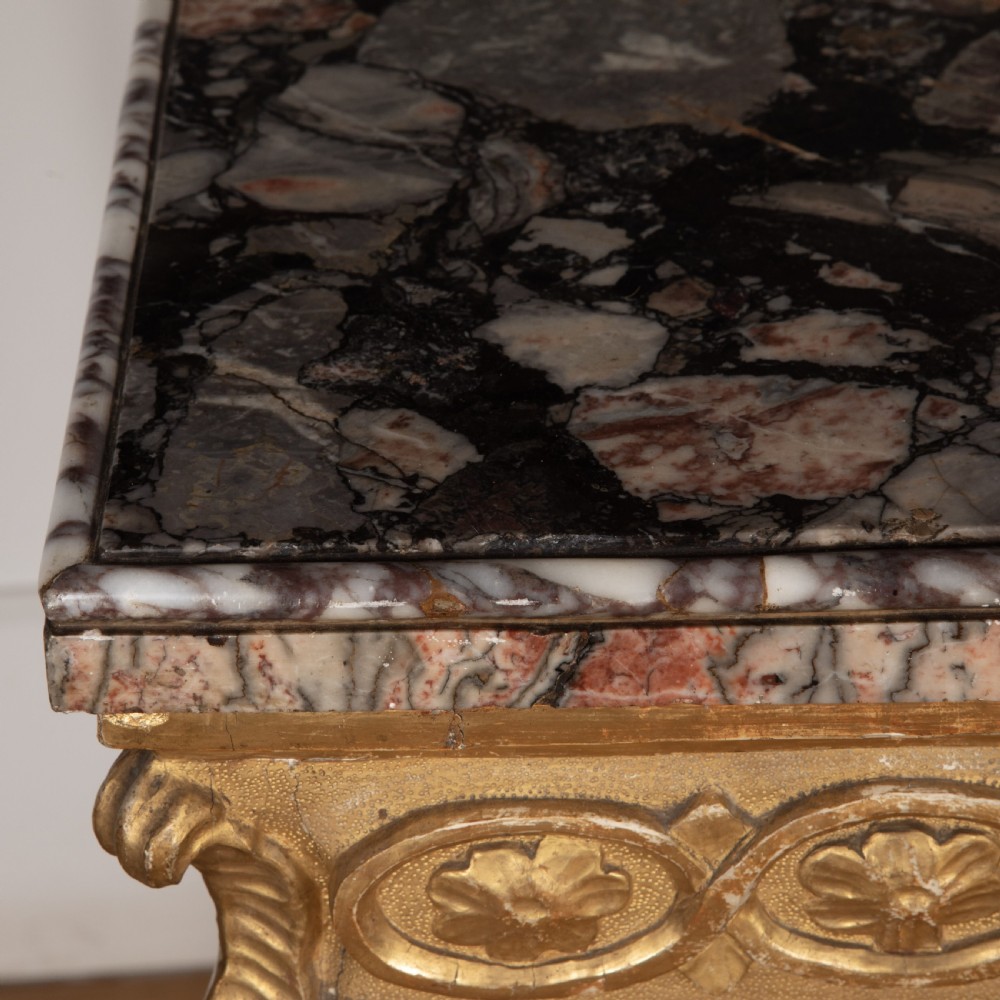An 18th-century giltwood console table featuring a dark mottled marble top, carved apron with rosette motifs, and cabriole legs linked by an X-shaped stretcher. View IX