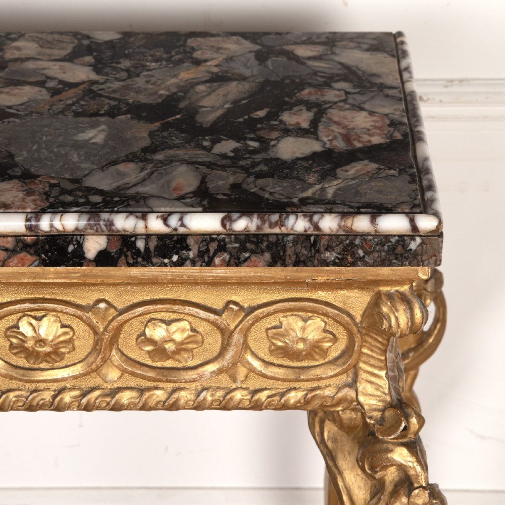 An 18th-century giltwood console table featuring a dark mottled marble top, carved apron with rosette motifs, and cabriole legs linked by an X-shaped stretcher. View X