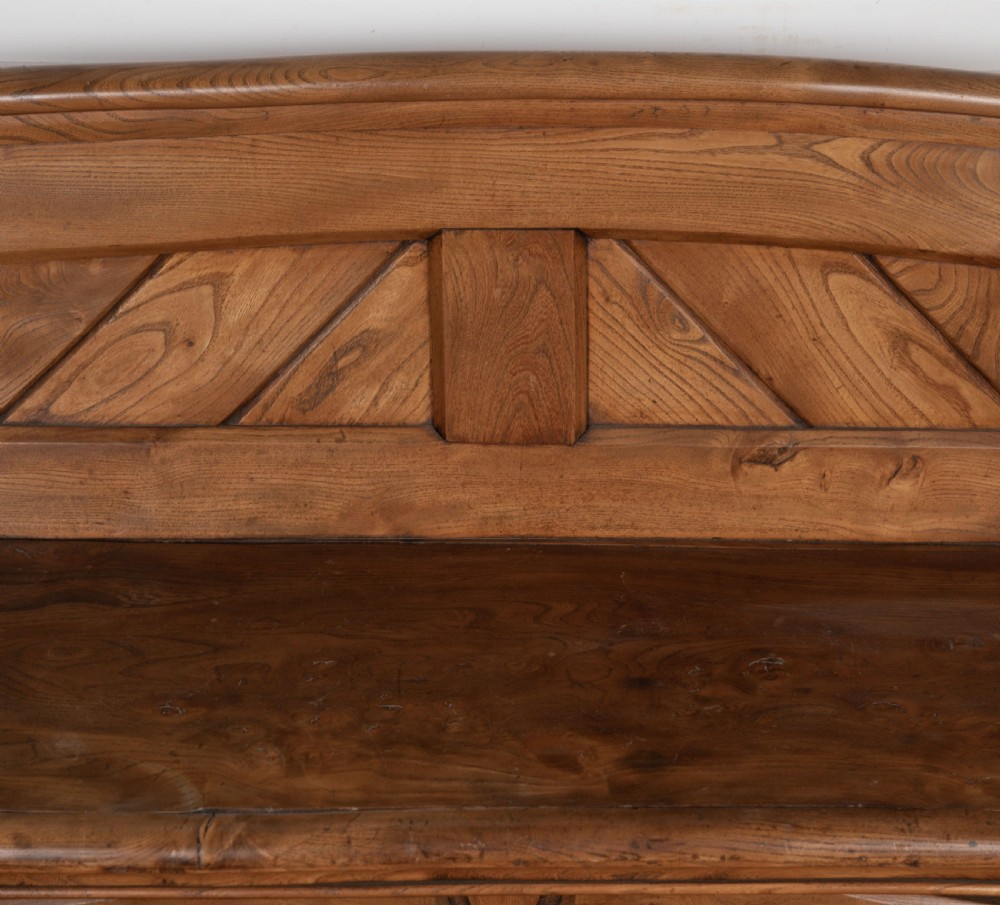 A 19th-century carved elm bench featuring pointed finial posts, a geometric panelled backrest, and trefoil cut-outs on the lower frame. View V