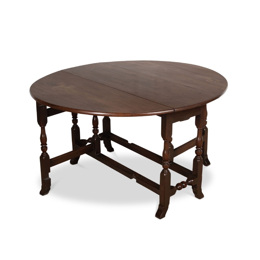 A dark brown Georgian walnut drop flap dining table featuring turned legs, bottom stretchers, an end drawer, and hinged oval leaves. View II