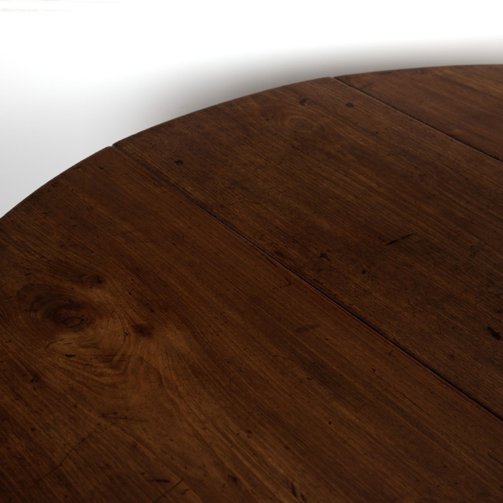 A dark brown Georgian walnut drop flap dining table featuring turned legs, bottom stretchers, an end drawer, and hinged oval leaves. View V