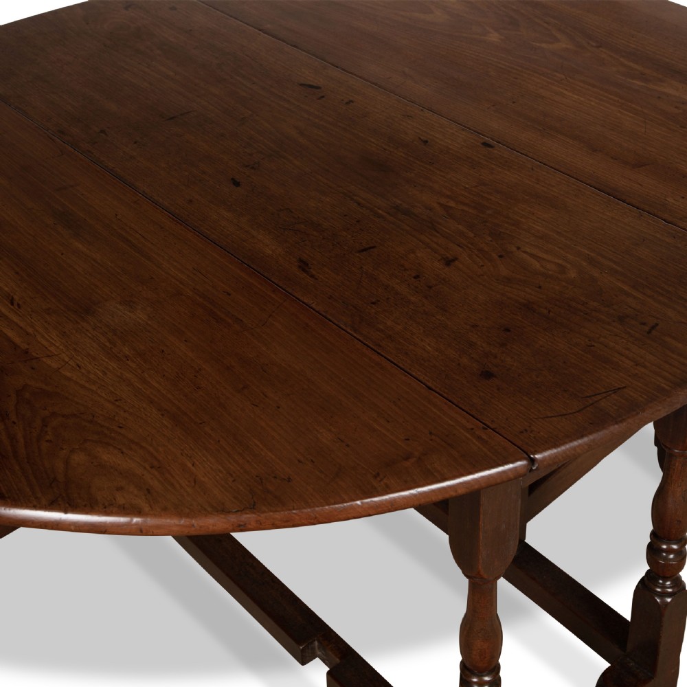 A dark brown Georgian walnut drop flap dining table featuring turned legs, bottom stretchers, an end drawer, and hinged oval leaves. View VI