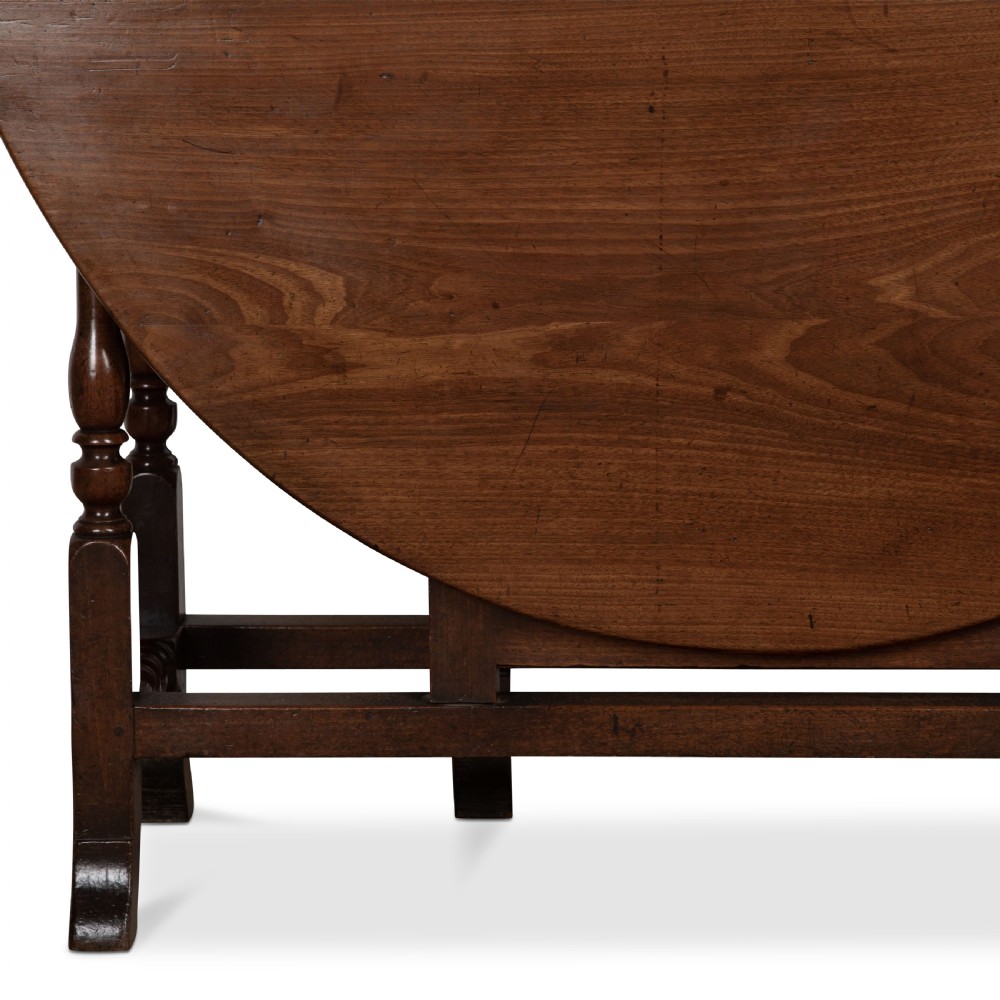A dark brown Georgian walnut drop flap dining table featuring turned legs, bottom stretchers, an end drawer, and hinged oval leaves. View VIII