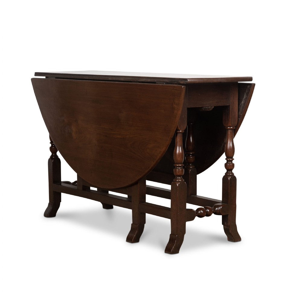 A dark brown Georgian walnut drop flap dining table featuring turned legs, bottom stretchers, an end drawer, and hinged oval leaves. View XI