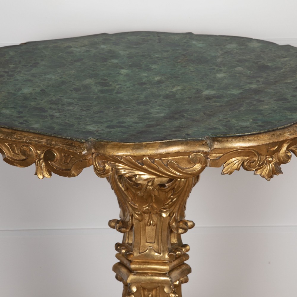 A 19th-century Italian centre table featuring a scalloped green marble top set upon a heavily carved giltwood pedestal base with scroll legs. View V