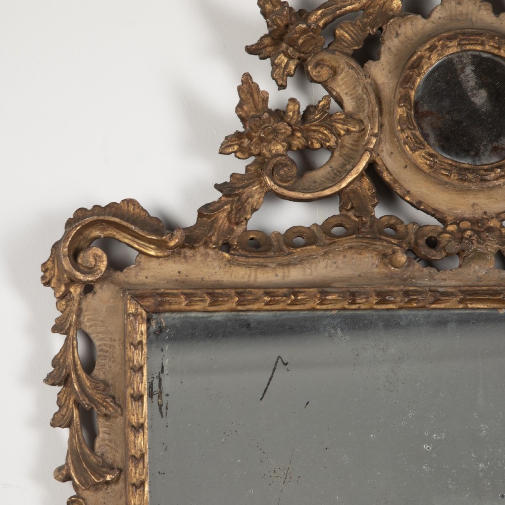 A rectangular eighteenth-century Italian giltwood wall mirror featuring a carved floral crest with an oval medallion and silvered glass. View IV