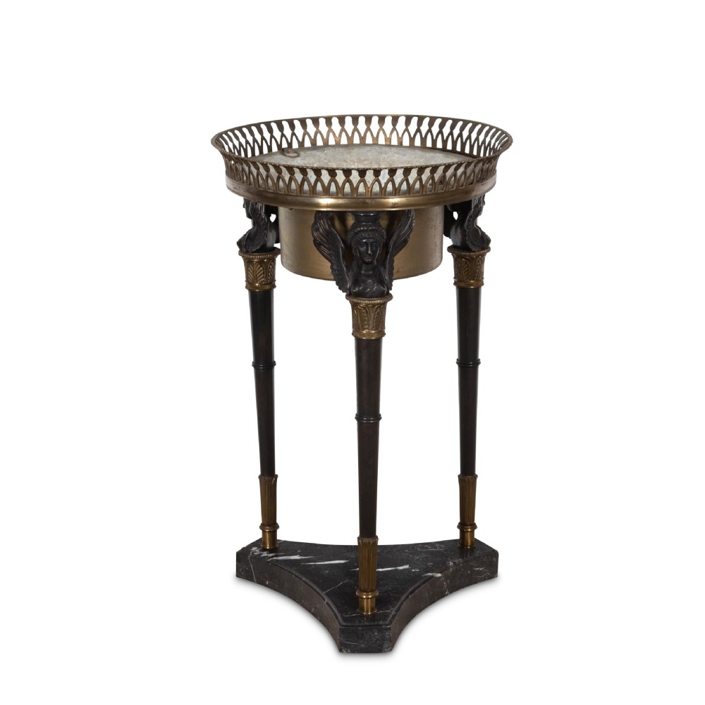 A 19th-century French Empire bronze Athenienne featuring a pierced metal gallery, winged caryatid legs, and a triangular dark marble base.