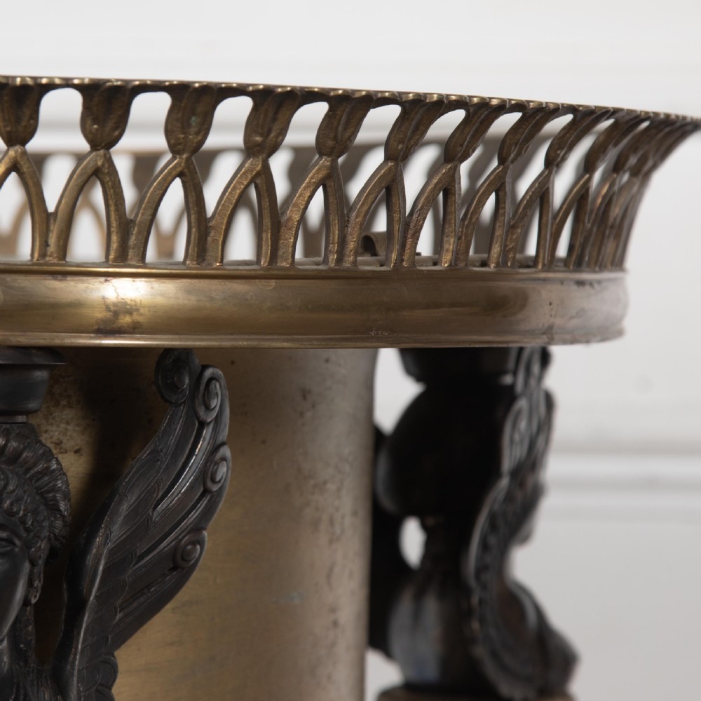 A 19th-century French Empire bronze Athenienne featuring a pierced metal gallery, winged caryatid legs, and a triangular dark marble base. View IV