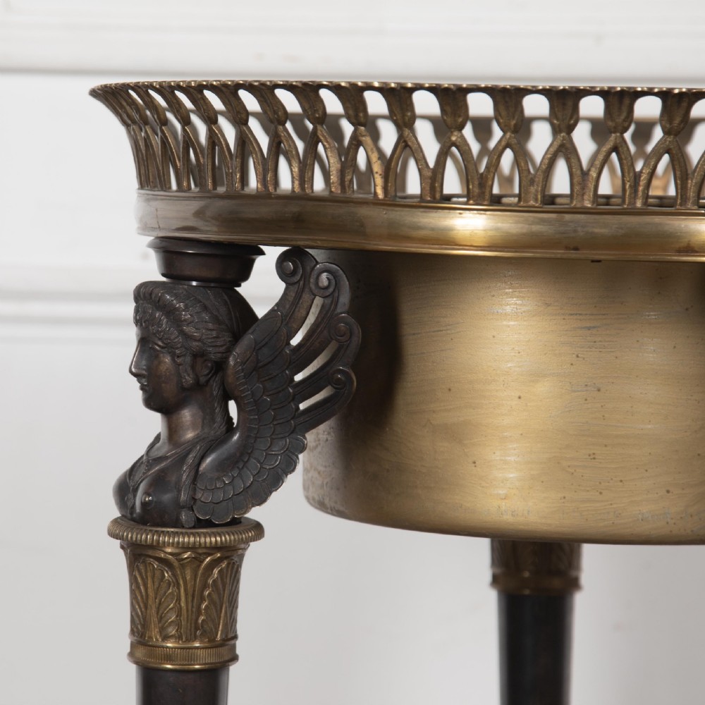 A 19th-century French Empire bronze Athenienne featuring a pierced metal gallery, winged caryatid legs, and a triangular dark marble base. View V