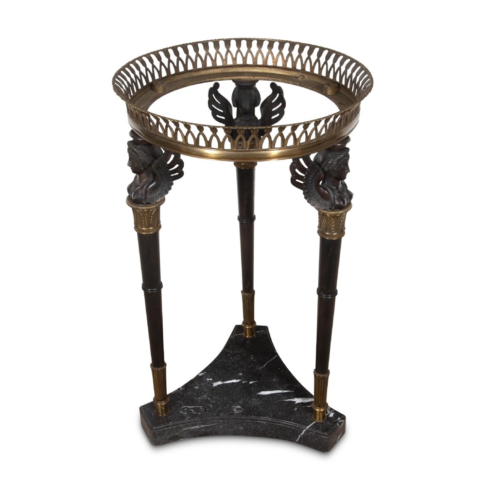 A 19th-century French Empire bronze Athenienne featuring a pierced metal gallery, winged caryatid legs, and a triangular dark marble base. View VI