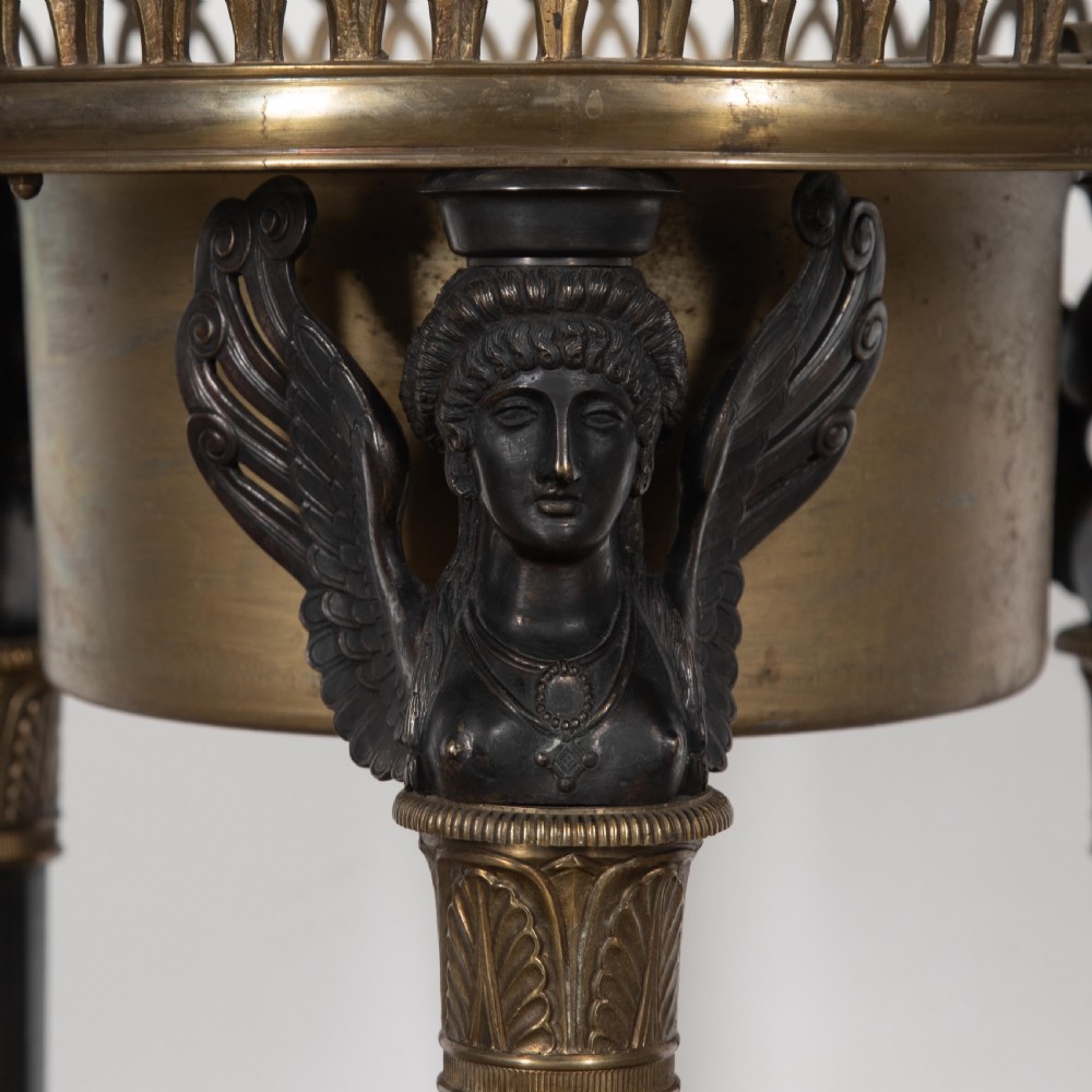 A 19th-century French Empire bronze Athenienne featuring a pierced metal gallery, winged caryatid legs, and a triangular dark marble base. View VII