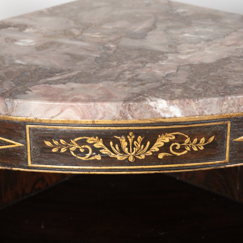 A pair of Regency-style black painted open corner cabinets featuring marble tops, gilt floral scrollwork friezes, and turned support columns. View VI