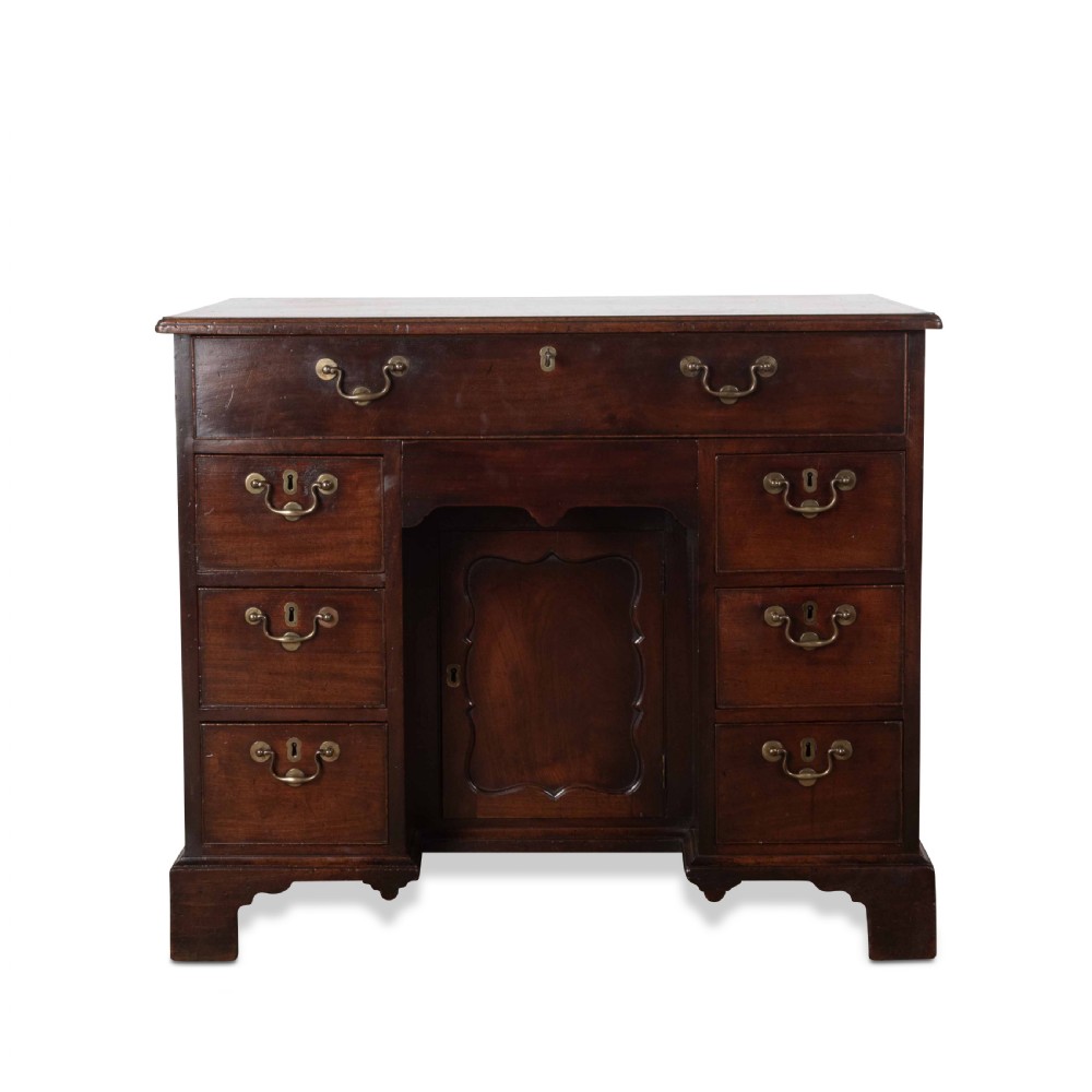 An 18th-century dark mahogany kneehole desk featuring a long top drawer above six side drawers and a central recessed cupboard door with brass handles. View IV