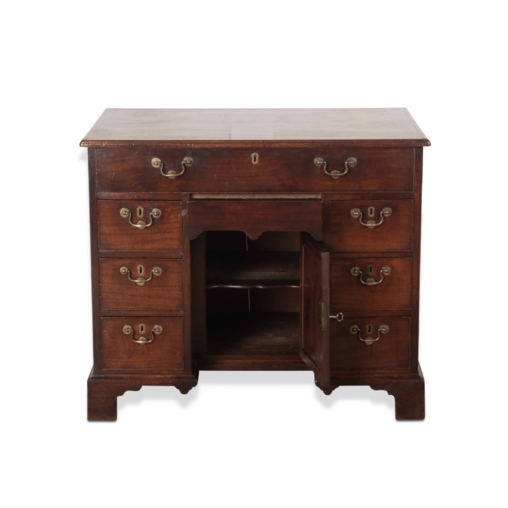 An 18th-century dark mahogany kneehole desk featuring a long top drawer above six side drawers and a central recessed cupboard door with brass handles. View VII