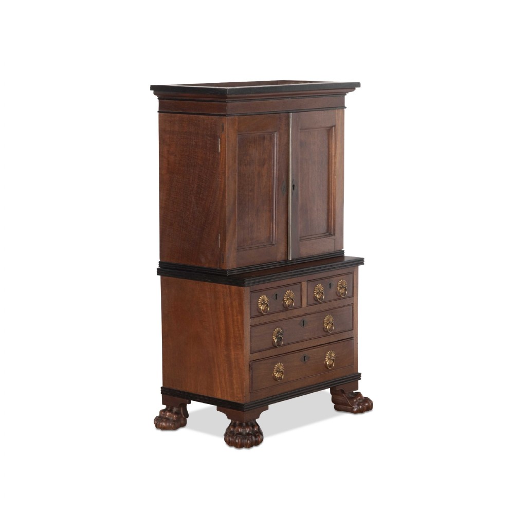 A 19th-century miniature Anglo-Indian hardwood linen press featuring panelled cupboard doors over three drawers, set on carved lion paw feet.
