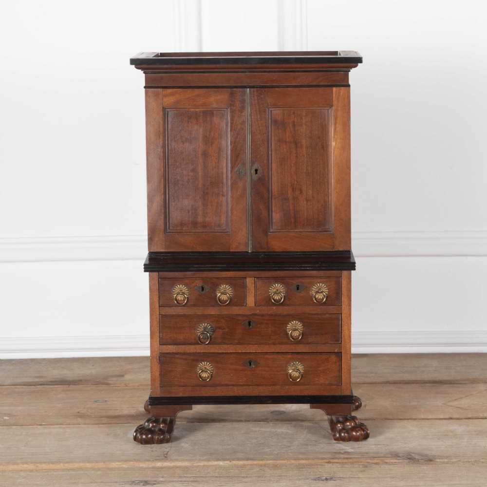 A 19th-century miniature Anglo-Indian hardwood linen press featuring panelled cupboard doors over three drawers, set on carved lion paw feet. View II