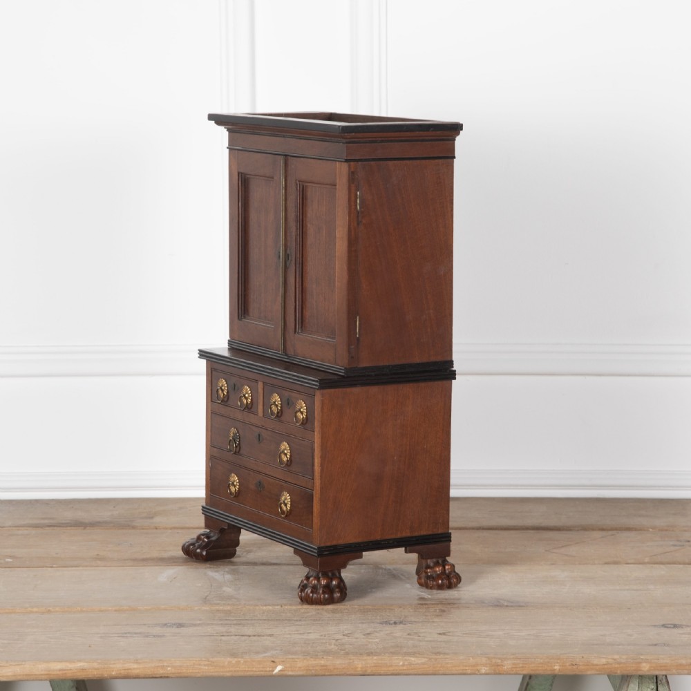 A 19th-century miniature Anglo-Indian hardwood linen press featuring panelled cupboard doors over three drawers, set on carved lion paw feet. View III