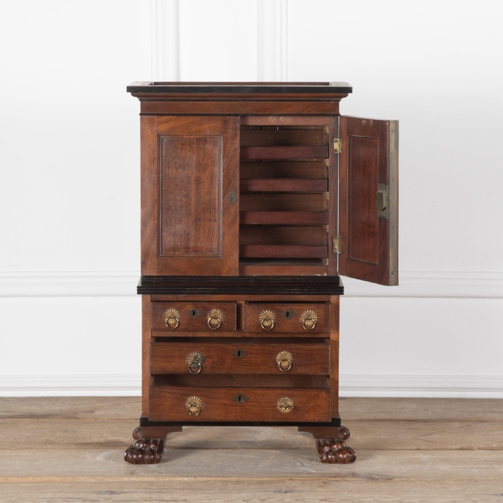A 19th-century miniature Anglo-Indian hardwood linen press featuring panelled cupboard doors over three drawers, set on carved lion paw feet. View IV