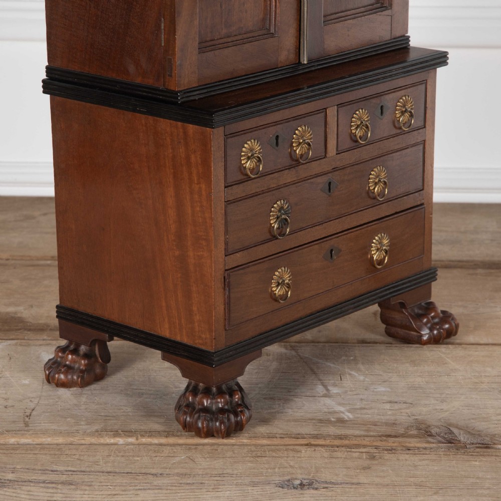 A 19th-century miniature Anglo-Indian hardwood linen press featuring panelled cupboard doors over three drawers, set on carved lion paw feet. View VI