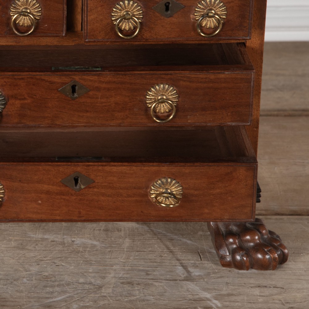 A 19th-century miniature Anglo-Indian hardwood linen press featuring panelled cupboard doors over three drawers, set on carved lion paw feet. View VII