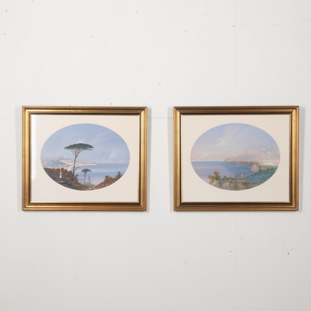 A pair of 19th-century gilt-framed landscape paintings depicting oval coastal views of the Bay of Naples in gouache on paper.