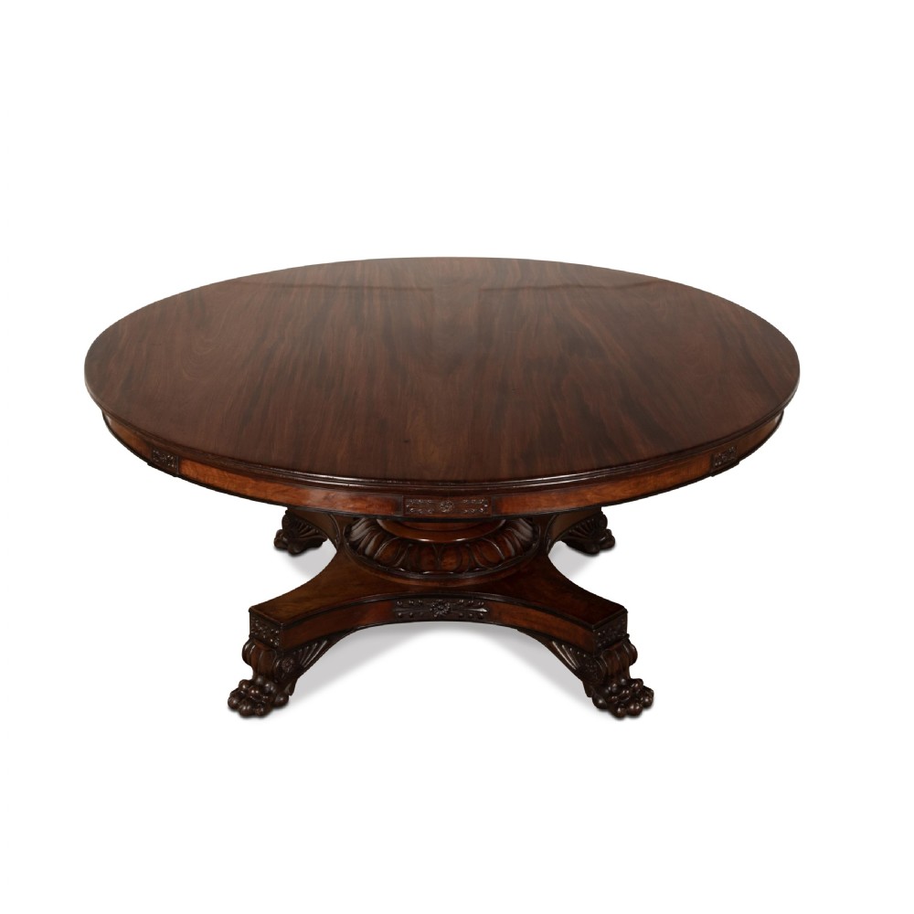 A circular Regency mahogany centre table featuring a carved frieze, a fluted pedestal column, and a concave four-legged plinth base with carved feet. View II