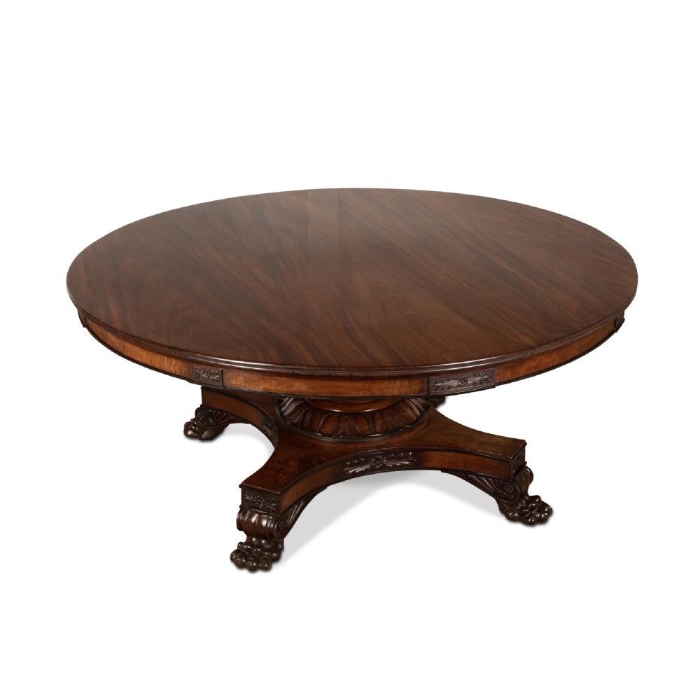 A circular Regency mahogany centre table featuring a carved frieze, a fluted pedestal column, and a concave four-legged plinth base with carved feet. View IV
