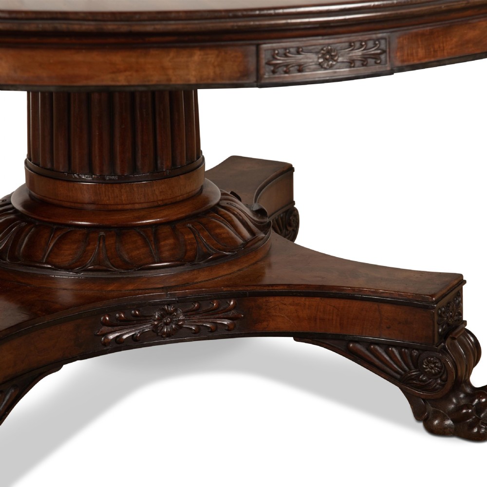 A circular Regency mahogany centre table featuring a carved frieze, a fluted pedestal column, and a concave four-legged plinth base with carved feet. View VIII