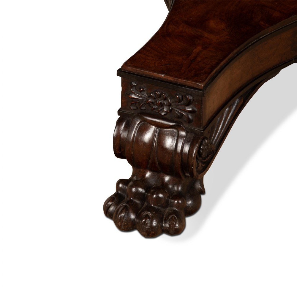 A circular Regency mahogany centre table featuring a carved frieze, a fluted pedestal column, and a concave four-legged plinth base with carved feet. View XI